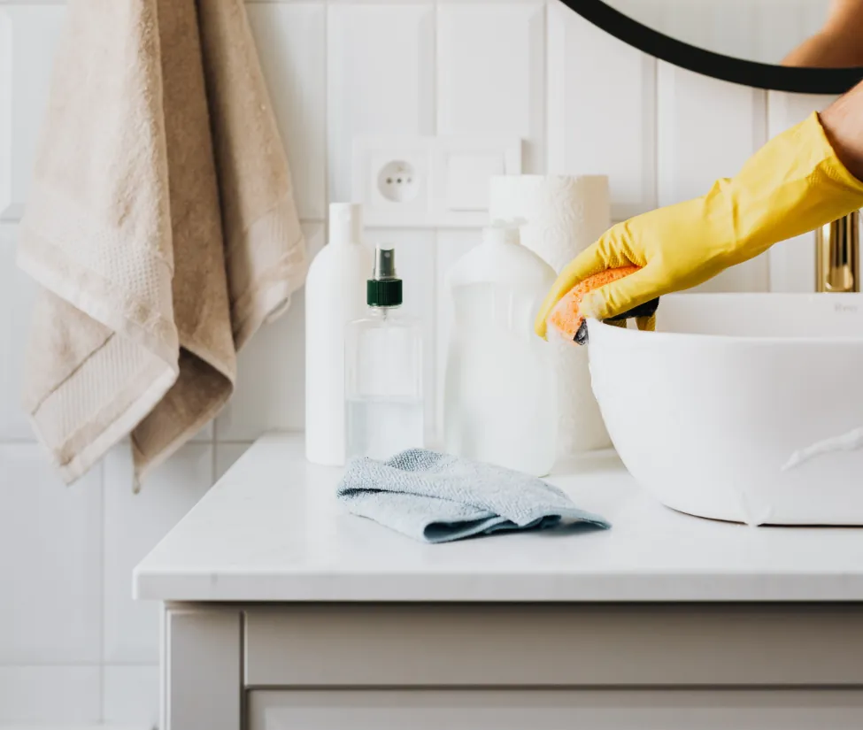 Professional Cleaning Services for Homes & Offices Spring Hill TN – yellow gloved hand cleaning a porcelain surface with professional cleaning supplies arranged around it