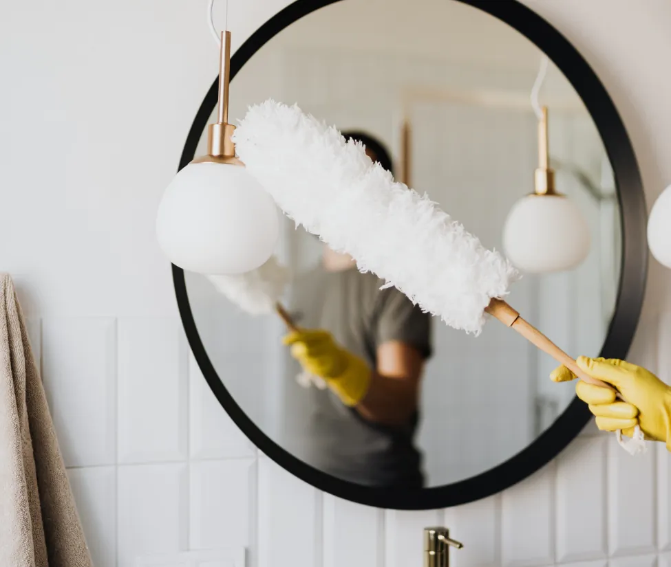 Professional Cleaning Services – cleaner dusting and polishing a mirror in a modern home